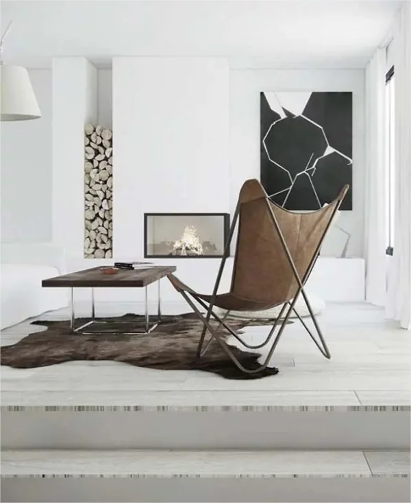 Minimalistischer Kamin Brennholzlagerung weisse Wand kleiner Tisch Pelzteppich Sessel
