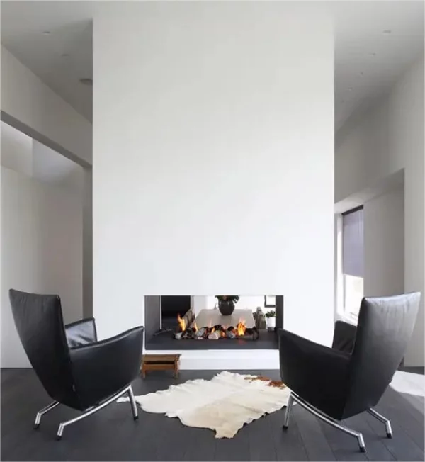 Minimalistischer Kamin minimalistisches Raumdesignweisse Trennwand doppelseitiger Kamin zwei Sessel schwarzer Boden