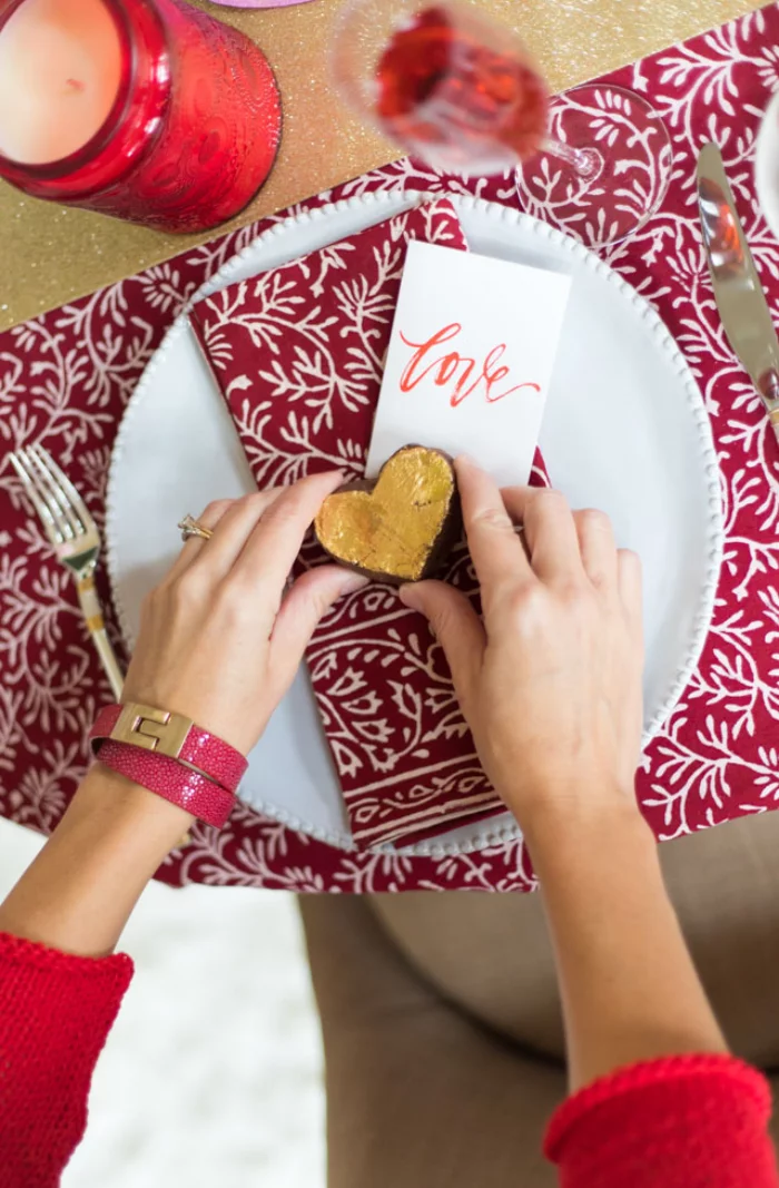 Romantische Tischdeko am Valentinstag gemusterte Decke in rot weiss kleines Herz in Goldgelb rote Kerzen