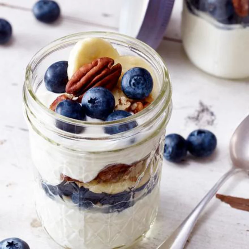 Griechischer Joghurt gesund lecker proteinreich mit Blaubeeren Nuesse Banan Stuecke