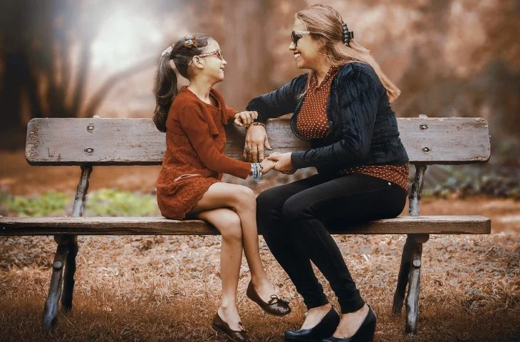 Mutter und Tochter sitzen auf einer Bank im Park