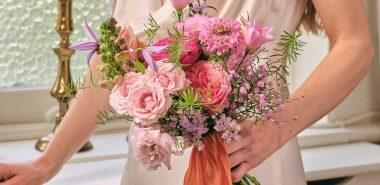 junge Braut trägt rosafarbenes Bouquet 